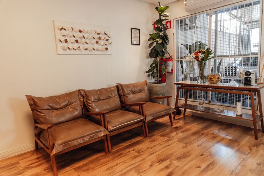 Recepção da Odontopoli com poltronas de couro e piso de madeira